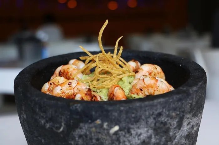 Guacamole con camarones en molcajete, con tiras de tortilla frita encima