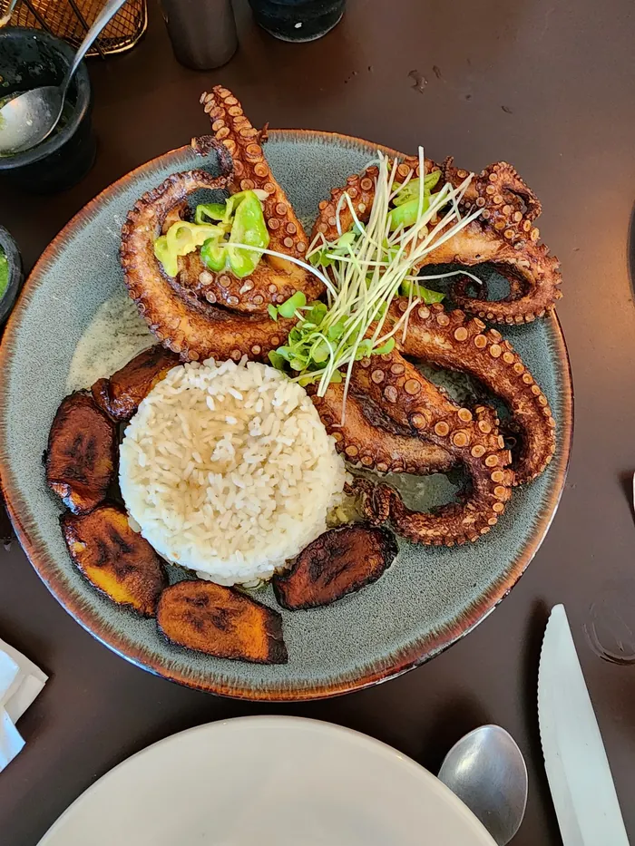 Pulpo frito sobre arroz blanco con plátanos fritos y germinado