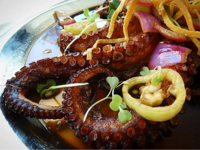 Pulpo frito en salsa con cebolla morada, aros de chile güero y tiras de tortilla