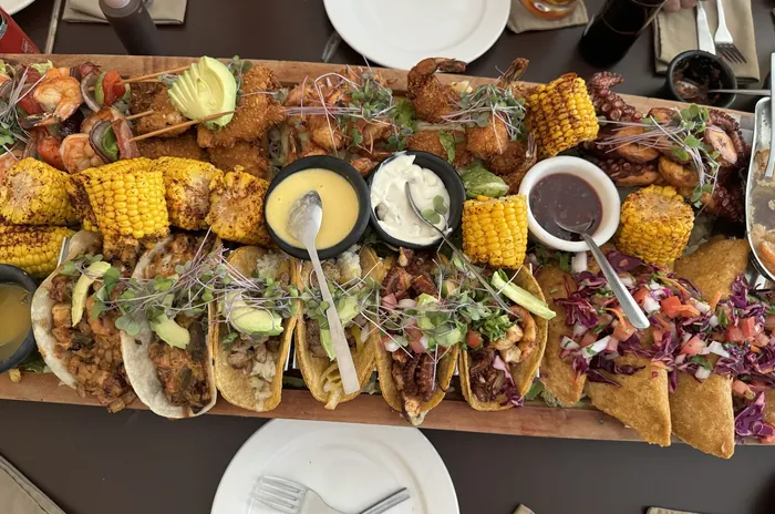Tabla para compartir con tacos, elotes y salsas